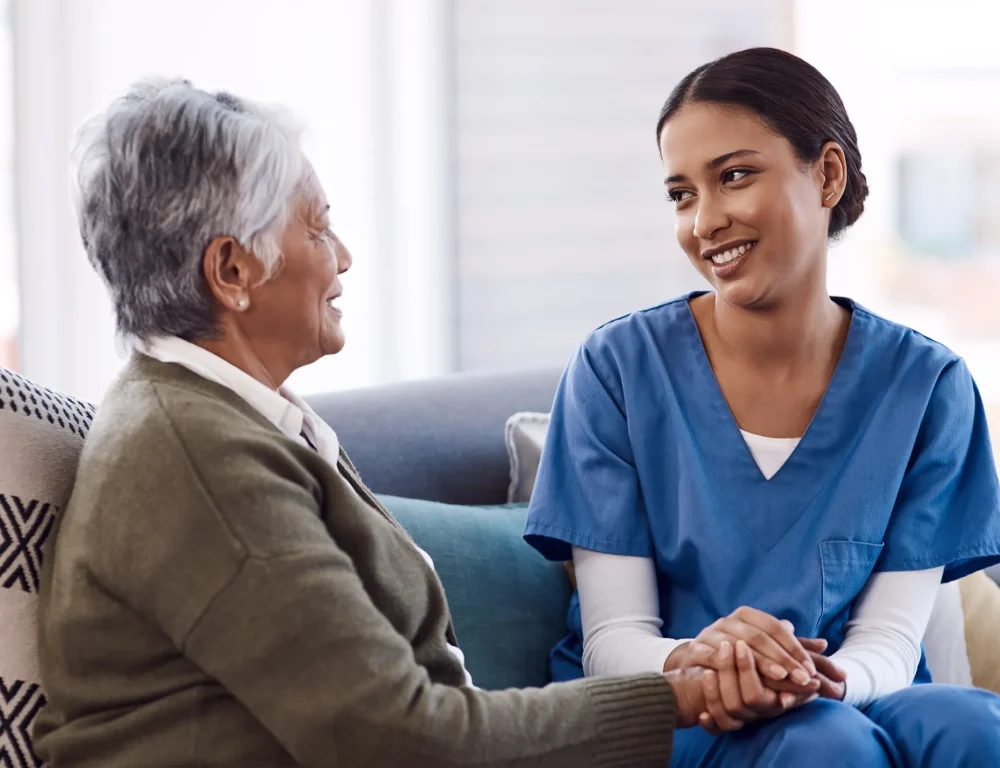 Nurse sat with elderly lady on a sofa.