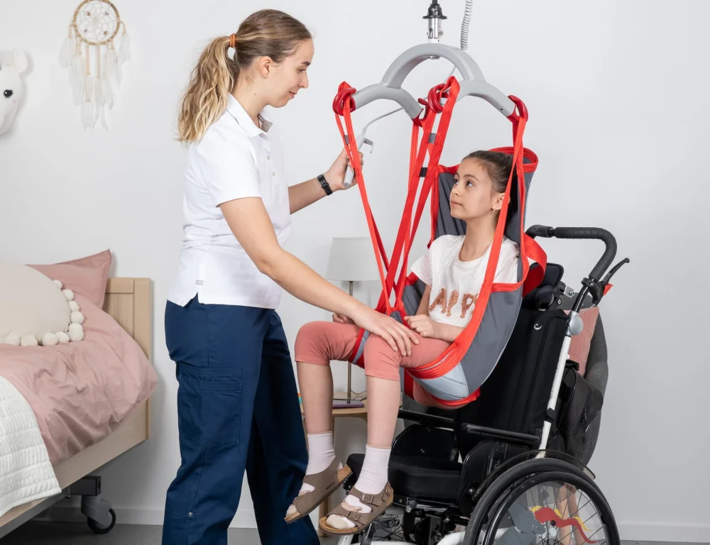 Young girl being moved into a wheelchair with a sling and hoist system.